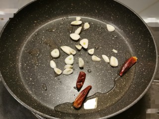 10、爆炒豆角,炒锅放入食用油 加热 放入蒜片和干辣椒 翻炒出香味