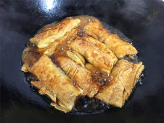 9、豆腐皮包肉,另取一锅，倒入适量水后加入生抽调味后把煎好的豆皮肉卷放入锅中。