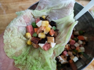 16、八宝百财福袋,将烫软沥水的白菜叶铺在手心里，用勺子将蔬菜丁放在白菜叶的中间。