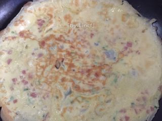 7、火腿蒜香鸡蛋卷,煎至周边微起凝固即可翻面煎熟。（煎得嫩会较软较好卷，颜色也较均匀哦）