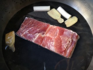 3、梅菜扣肉,将带皮猪五花肉冷水下锅，加葱白姜片和料酒煮透。