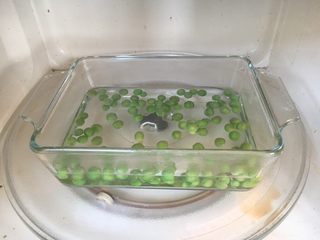 9、鲜虾土豆泥,豌豆剥皮,微波炉里容器水开后,放入豌豆,微波3分钟,捞出豌豆,沥干水分备用。