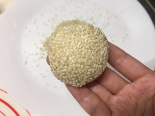 8、花环汉堡(植物油直接法),盘子里放上白芝麻,面团不用醒发,表面喷水或者刷水,在白芝麻上轻滚一下,芝麻就很均匀的沾上了