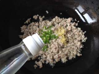 5、炒苍蝇头,肉末炒至变白后倒入料酒、葱花和姜末炒制片刻