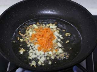 10、娃娃菜卷肉,锅内倒入适量食用油,爆香蒜末、胡萝卜碎。因为有小孩,所以没有放辣椒,喜欢吃辣的,这里可以加一些辣椒、剁椒都可以。