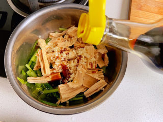 19、芹菜拌腐竹,酱油倒入一点,不用太多。然后把花椒油也倒进来,如果想要蒜香味更香浓,可以在花椒油做好的时候直接浇在蒜末上,大蒜经过热油的淋烫立刻会闻到蒜香气。