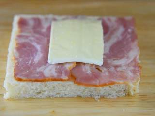 3、不只是一份煎蛋吐司，还有均衡的营养和生活的惬意,吐司片打底依次铺上一片芝士、对切好的培根.，再一片芝士，最后再拿一片吐司片夹住。