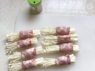 3、金针菇培根卷,取一小撮金针菇，用培根卷紧，再别一根牙签