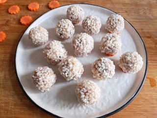 14、团团圆圆——珍珠圆子,将裹好糯米粉圆子放在胡萝卜片上。