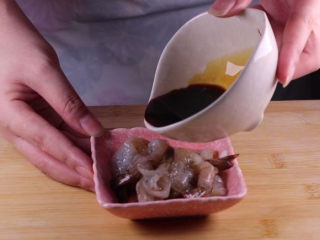 7、丝瓜换种新鲜做法,比炒蛋还要好吃百倍,将处理好的虾装入小碟子中,倒入一小瓶盖的料酒、一小勺的生抽,用筷子拌匀后腌制备用。