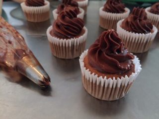 16、巧克力杯子蛋糕,取出巧克力甘那许，隔温水再次将巧克力甘那许拌匀，静置至裱花状态后装入有8齿裱花嘴的裱花袋内