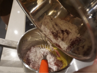 5、红丝绒蛋糕卷,把已过筛的粉类倒进奶锅里继续搅拌均匀