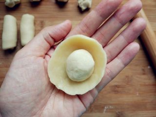 3、豆沙蛋黄酥, 取一块水油皮，两手大拇指在内，其余手指在外，边捏边转动，形成一个中间凹的圆饼，把油酥团成球，放在中间