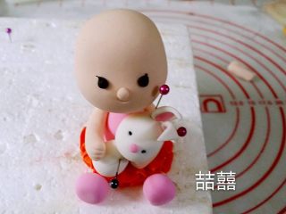 22、翻糖蛋糕--树桩上的小女孩儿,中间丢了几张图。搓一个小水滴型做兔子的身体，用做小孩儿头的方法坐兔子的头，再粘上耳朵，贴在小孩儿身前，再做出手臂抱的动作，然后搓4个小球做兔子的四肢