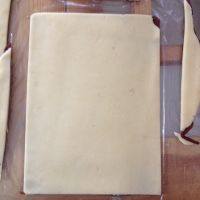 10、黑纹奶酪饼干,将奶酪面团也擀成差不多大小的形状，铺在刷了清水的巧克力面皮上，将面皮四周不规则的部分切去。