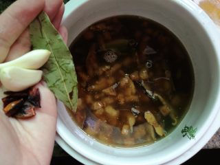 9、家常卤肉饭,汤水滚开后,倒入砂锅内,加入冰糖,蒜头,八角,香叶,还有炸过的洋葱酥,再倒入少量清水没过食材。