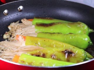 16、往青椒里塞入半斤金针菇,这味道绝了!,来回翻面,将青椒两面简直起虎皮。金针菇在煎的过程中会出水是正常的。