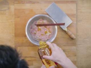 11、过油肉配酱焖鱼头,2-2将切好的猪里脊片倒入盆中,再挤适量柠檬汁,倒入适量花生油备用