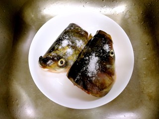 2、蒜香豆豉蒸鱼头,鱼头冲洗一下,撒一点盐,在表面抹匀,再冲洗干净。