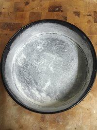 2、樱桃芝士派,8寸圆模内涂上一层软化的黄油，再洒上一些面粉，摇晃圆模，使面粉均匀粘在圆模上，倒出多余面粉。