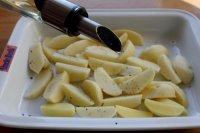 3、苹果柠香烤鸡腿,将土豆放入烤盘里,撒点胡椒、盐,浇点油拌均匀