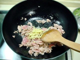 10、腐乳爆肉,炒勺上火烧热,注入适量油,下入肉片煸炒,肉片变色后放入姜丝翻炒。