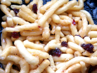 5、自制蔓越莓沙琪玛,关火，将蔓越莓干和炸好的面条倒入锅中，快速翻动，使每一条都均匀黏上糖浆。趁热速度要快，糖浆一凉会很快凝固