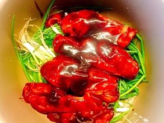 12、电饭锅版叉烧肉,电饭锅内放入洗净的小葱,放入适量姜片去腥,最上面垫上腌制好的肉块;