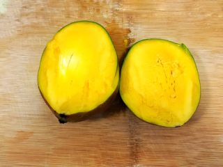 3、颗粒感十足的芒果芭蕉壁挂奶昔,芒果用刀一分为二