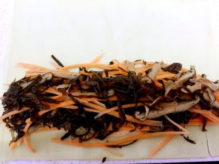 6、健康素食之豆腐皮卷素菜,取一张铺开,在末端铺上胡萝卜丝、香菇丝、黑木耳丝