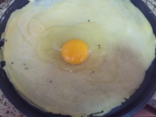 8、深夜食堂之煎饼果子,打入一个鸡蛋，用铲子，慢慢的一圈一圈的把鸡蛋，摊在饼上；