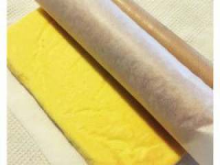 7、圣诞巧克力劈柴蛋糕,烘烤好的蛋糕坯马上取出，另裁 剪一张烘焙油纸铺在台子上，蛋糕 坯深色一面向下放在烘焙油纸上， 快速轻轻地将黏在蛋糕坯的烘焙油纸揭掉（注 意：因糕体还有热度，揭掉烘焙油纸时要小心， 避免破坏糕体）。趁着热度连同底部的烘焙油纸 一起轻轻卷起（如果晾凉了糕体会变干不好 卷）。