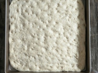 4、混合香草佛卡夏,用擀面杖擀成和烤盘一样大的正方形后把面团移到烤盘，再松弛15分钟