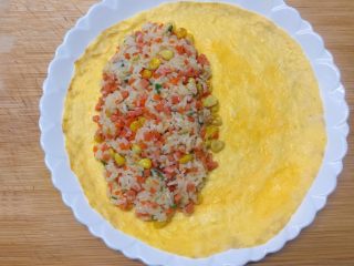16、百变鸡蛋+蛋包饭,然后将炒好的米饭放在蛋饼的二分之一处，边缘位置要留空，再用勺子将米饭轻轻压实。