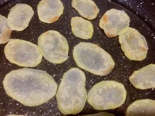 8、平底锅版健康无油香脆薯片,慢慢烘至一面脱水微黄状态，用筷子夹起土豆片翻面