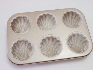 14、百香果柠檬玛德琳,然后撒上少许低筋面粉,可方便脱模(面粉撒多了,可倒扣模具抖掉多余的面粉)