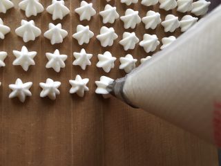 10、宝宝零食酸奶溶豆,一手握住收口端，一手握住裱花嘴开始挤豆豆吧。我用的油布，也可以用油纸，此时烤箱预热，上下火100度，60分钟。