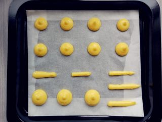 11、 酥皮蘑菇泡芙,将面糊装入剪口的裱花袋中，在铺了油纸的烤盘上挤出圆形和稍细的长条形。每个泡芙之间要留出足够的膨胀距离