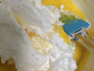 6、葡萄干戚风蛋糕,如图将1/3蛋白倒入蛋黄面糊,用上下翻拌的手法拌匀;