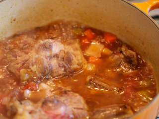 9、烩牛尾,逐渐倒入红酒并使用木炒勺轻刮锅子底部，帮助焦糖色物质溶于汤汁中，随后放入牛尾，将烧好的高汤浇在牛尾上，和牛尾基本齐平就好，不用太多汤汁，盐、胡椒调味并试味