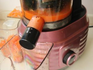 3、胡萝卜虾饺,启动原汁机，从投料口投入胡萝卜条，下不去的可以用推杆推一下，工作中的原汁机，汁渣开始分离。