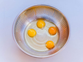 1、千层蛋糕,取一个大盆放入四颗鸡蛋，用打蛋器充分打散