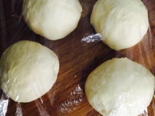 14、奶黄面包,取出排气，分四个团，盖保鲜膜，醒15分钟！