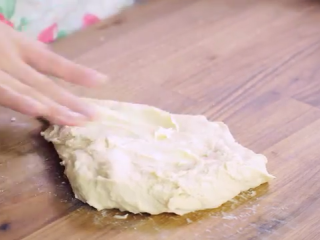 2、火腿芝士面包,面团成型后,转移到案板上,进行揉面,直至能扯出薄膜,加入1/3事先软化的黄油,开始揉搓