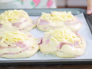 11、火腿芝士面包,烤箱预热180度,鸡蛋打散,在面包表面均匀刷一层蛋液,撒上奶酪丝