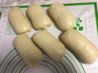 9、烫种牛奶吐司,自上而下卷成圆筒状，全部卷好盖保鲜膜静止松弛10-15分钟。