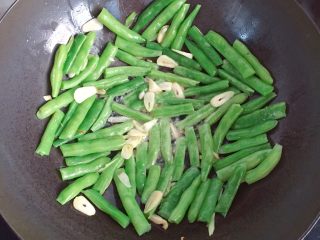 9、干煸四季豆,倒入焯好的四季豆翻炒均匀后用锅铲铺平(这样可以使每根四季豆均匀受热)