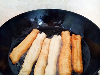 11、早餐油条,放入油条胚用筷子快速翻面，还需要多次翻面中小火炸。