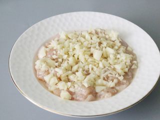 12、蒜蓉鸡胸肉,腌制好的鸡胸肉放入一个盘子里铺平，撒上蒜末。