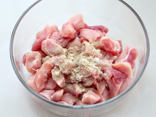 2、菠萝咕咾肉,将切好的肉块放入容器中,加料酒、盐、糖和胡椒粉拌匀后腌制半个小时